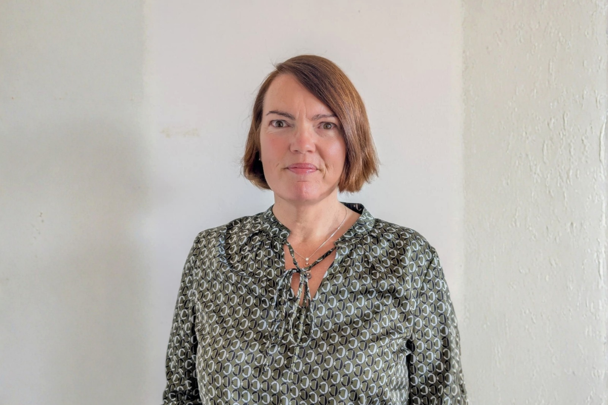 a woman smiling, standing against a white background