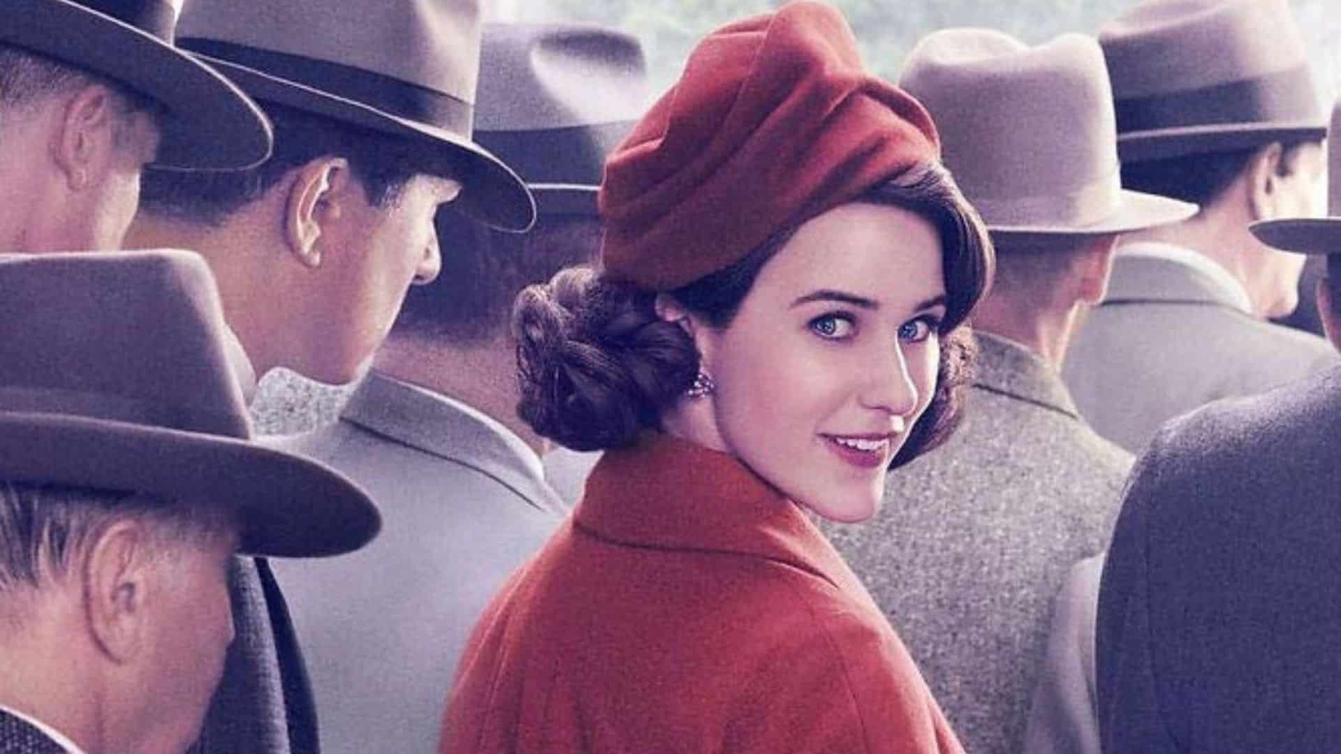 Mrs. Maisel looks toward the camera in a crowd of men dressed in grey
