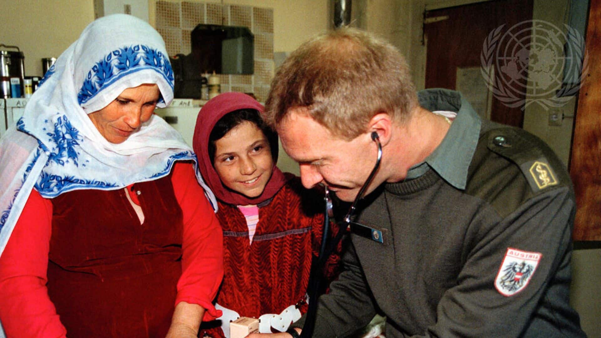 A United Nations humanitarian aid worker checks the heartbeat of a baby, while two women look on fondly